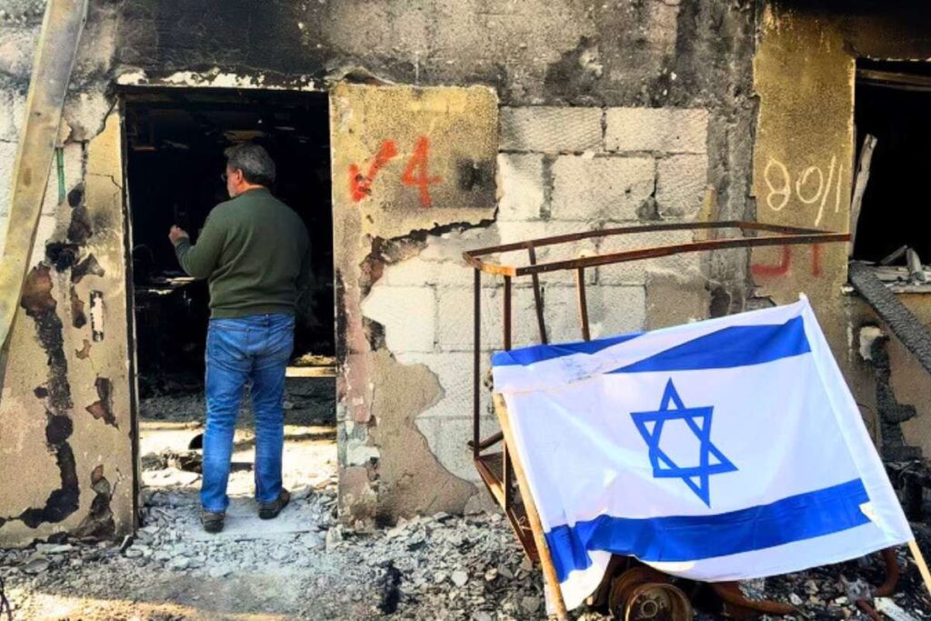 Rabbi Curt Landry walks in the doorway of a bombed and burned building, depicting the horrific destruction of the Kibbutz Kafar Aza in the aftermath of October 7th