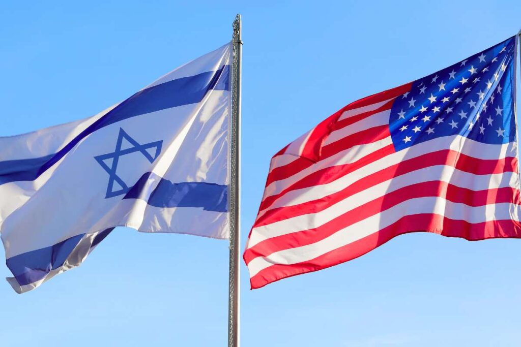 American and Israeli flag waves against the bright blue sky showing the two nations joined in unity.